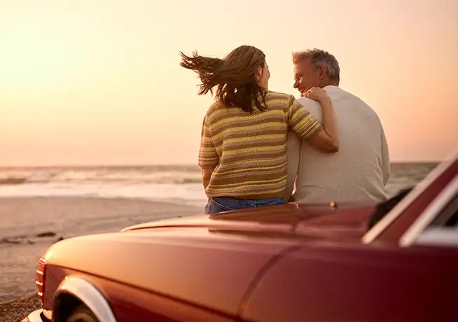 retired senior couple sitting on car at beach wathing sun long term care anchor pointe wealth annapolis chester maryland